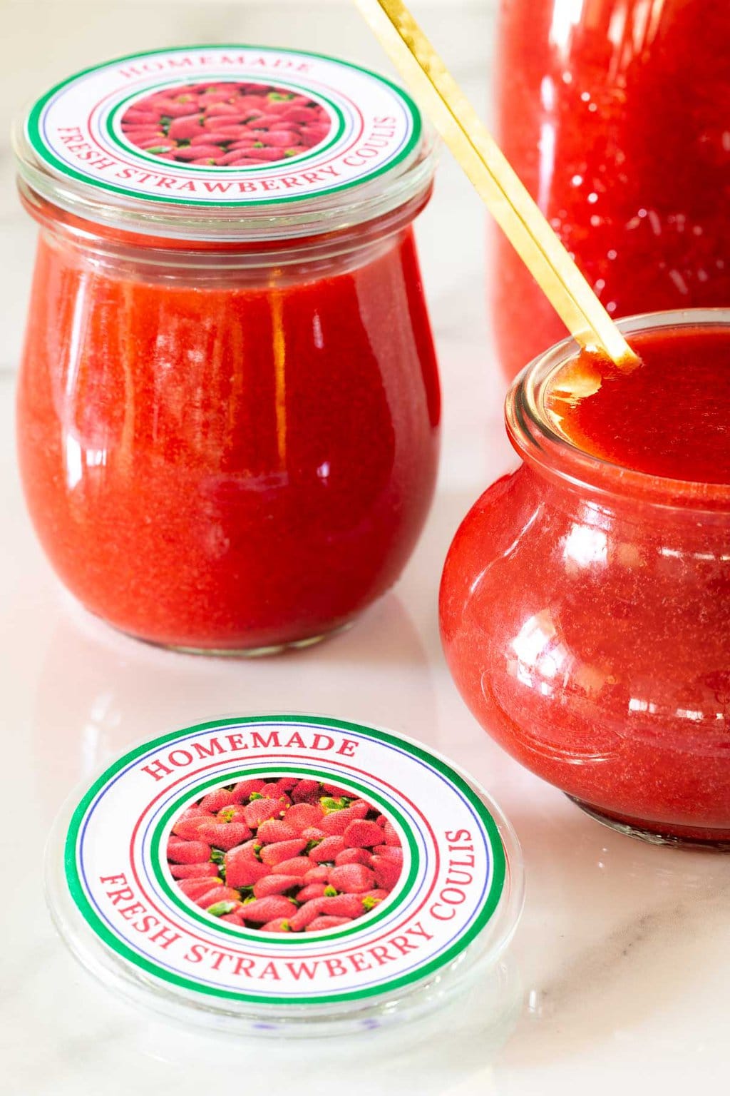 Vertical closeup photo of jars of Ridiculously Easy Strawberry Coulis with custom labels for gift giving.