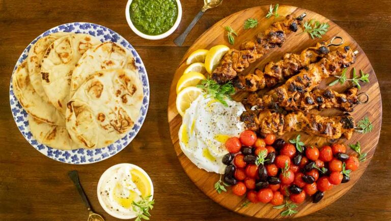 Overhead horizontal photo of Middle Eastern Grilled Chicken with Toum (a delicious Lebanese garlic spread) on a round wood platter.
