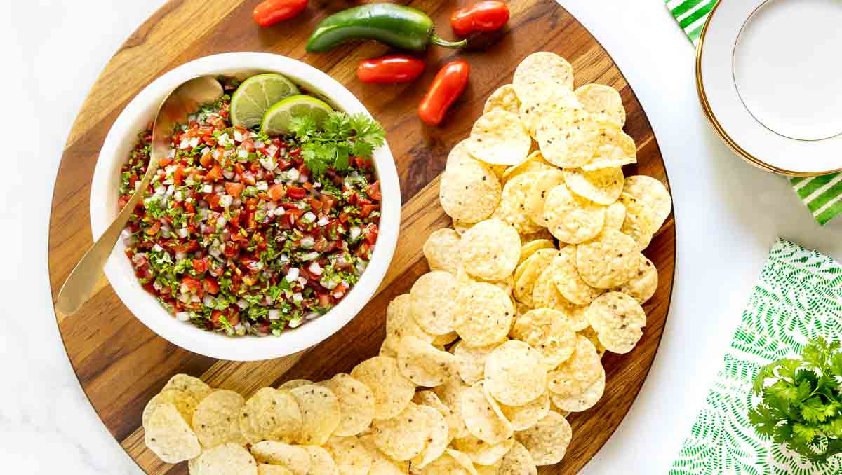 Best Ever Pico de Gallo (Salsa Mexicana) - thecafesucrefarine.com Overhead photo of a bowl of Best Ever Pico de Gallo (Salsa Mexicana) surrounded by fresh peppers and tortilla chips.