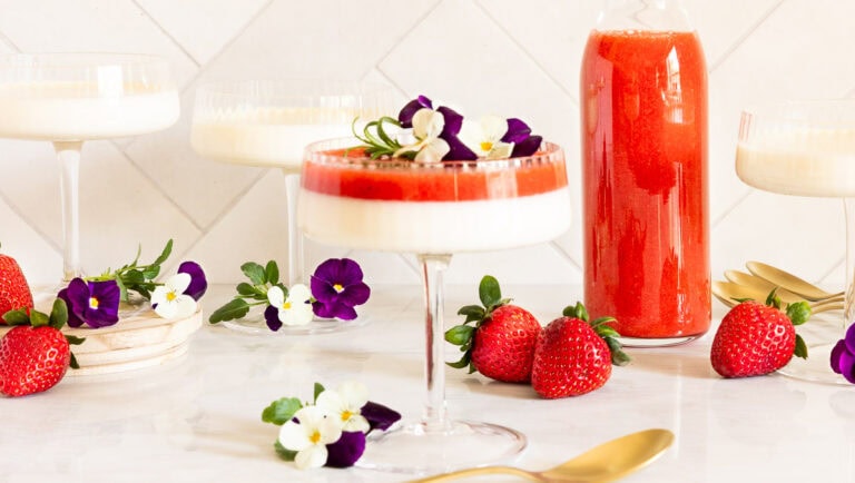 Horizontal photo of a glass dessert dish filled with Ridiculously Easy Lemon Vanilla Bean Panna Cotta.