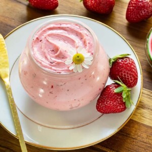 Horizontal closeup photo of a Weck jar of Ridiculously Easy Fresh Strawberry Butter on a wood platter.