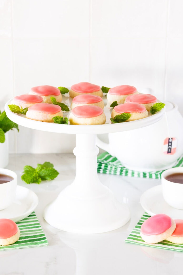 Strawberry Lemonade Meltaway Cookies on a white cake stand garnished with mint.
