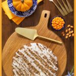 Pumpkin Crumb Cake on a round wooded cutting board iwth a serving utensil and a bowl of orange jelly beans.