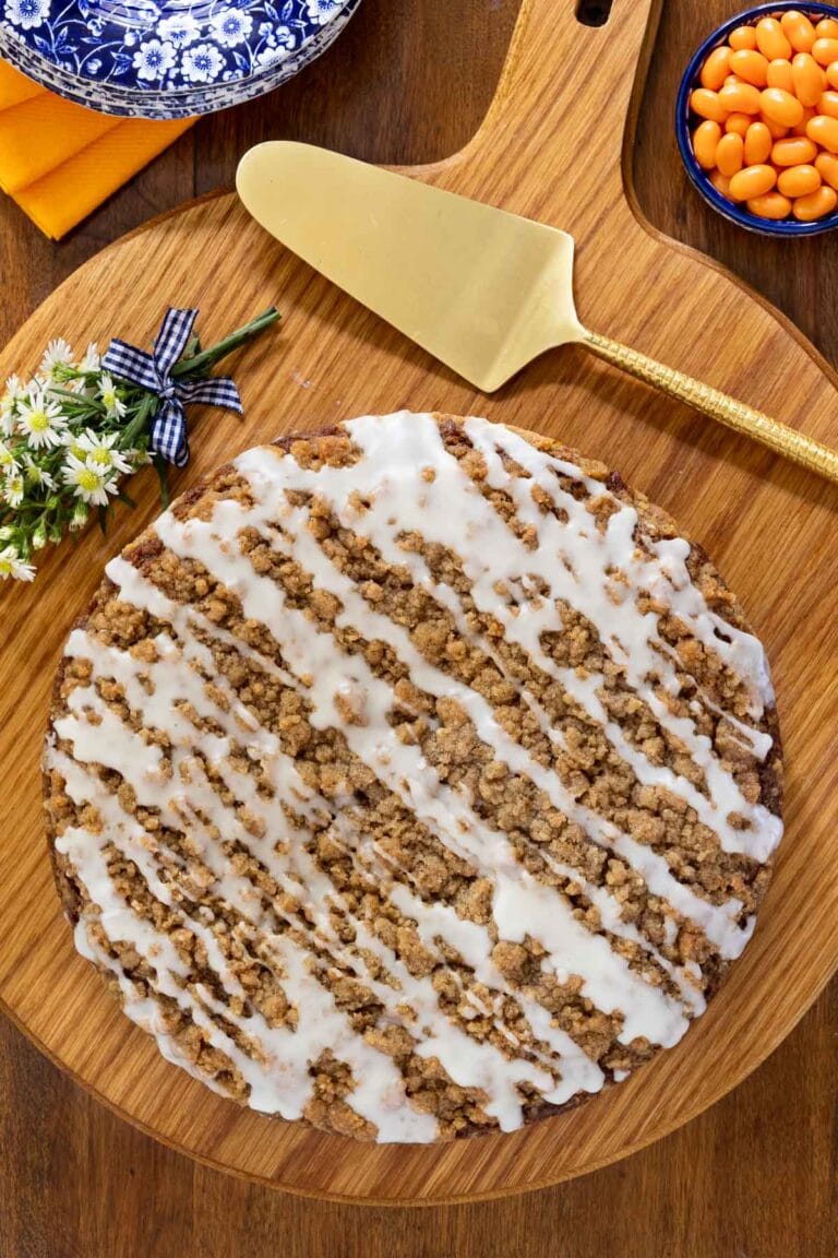Pumpkin crumb cake on a wooden cutting board with a gold cake server.