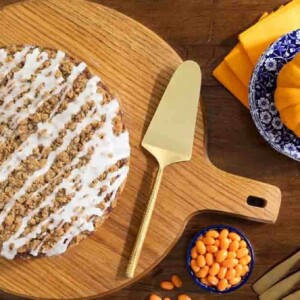 Horizontal overhead photo of a Bakery Style Pumpkin Crumb Cake on a round wood serving plate.