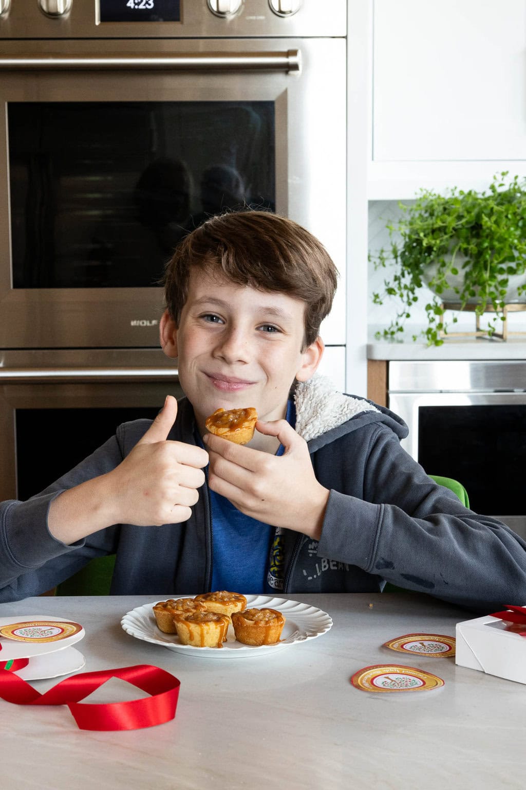Vertical photo of Luke giving a "thumbs up" approval of a batch of Ridiculously Easy Caramel Apple Shortbread Tarts.