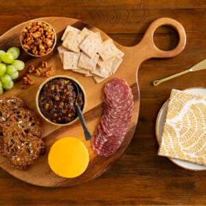 Overhead horizontal photo of a wood appetizer tray featuring Caramelized Fig Jam with Honey and Pears.