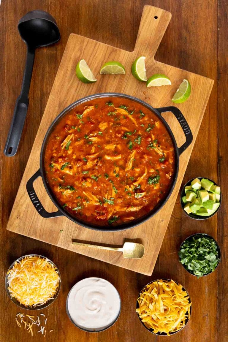 Chicken Poblano Soup in a cast iron dutch oven with small bowls of toppings.