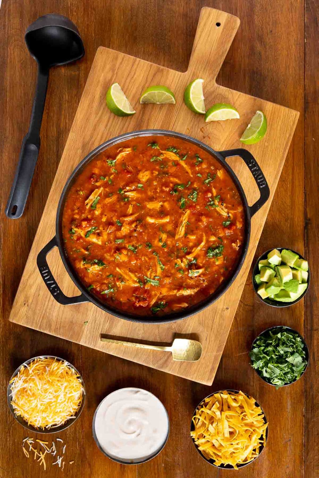 Chicken Poblano Soup in a cast iron dutch oven with small bowls of toppings.