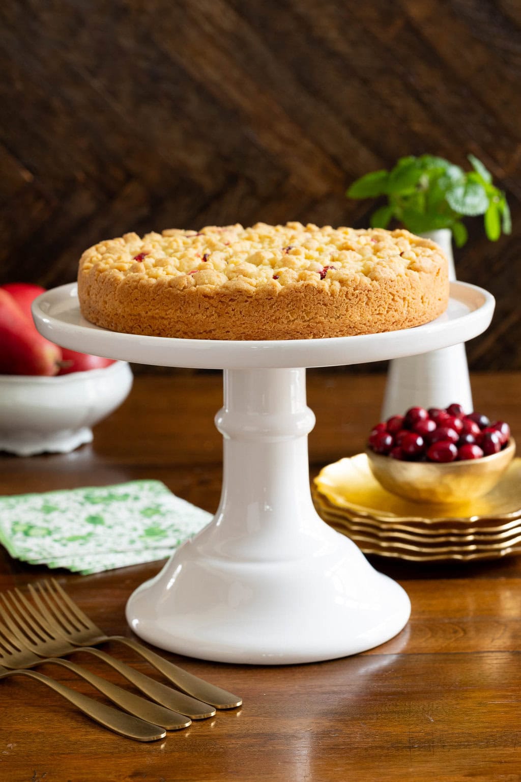 Cranberry Pear Shortbread Tart - thecafesucrefarine.com Vertical photo of a Cranberry Pear Shortbread Tart on a white pedestal serving plate and surrounded by fresh cranberries and pears.