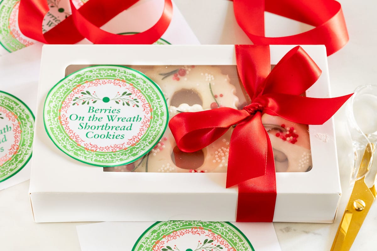Horizontal photo of a decorative box of Berries on the Wreath Shortbread Cookies with custom labels for gift giving.