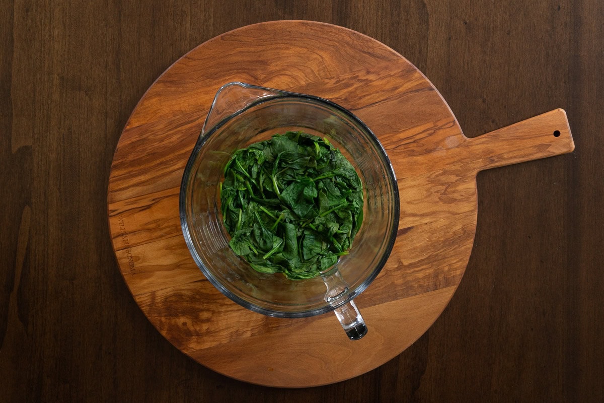 Horizontal overhead photo of a measuring bowl of the amount of spinach used in making Marry Me Chicken and Spinach Risotto after 2 minutes in the microwave.