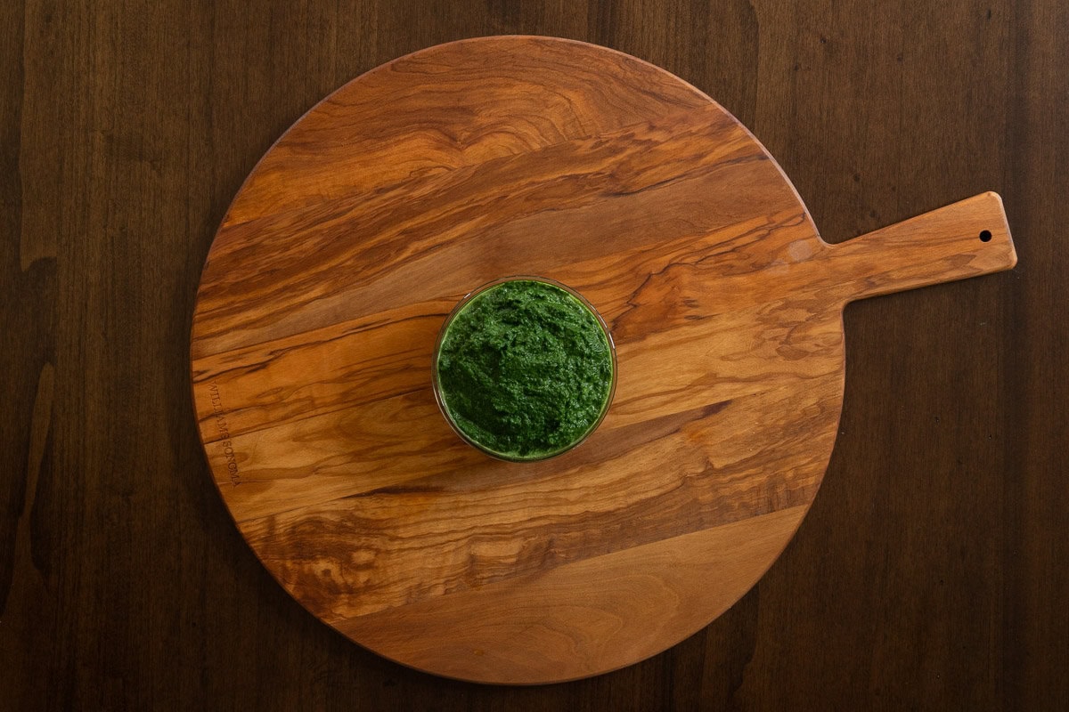 Horizontal overhead photo of a small bowl of spinach after it is cooked and put in the food processor for making Marry Me Chicken and Spinach Risotto.