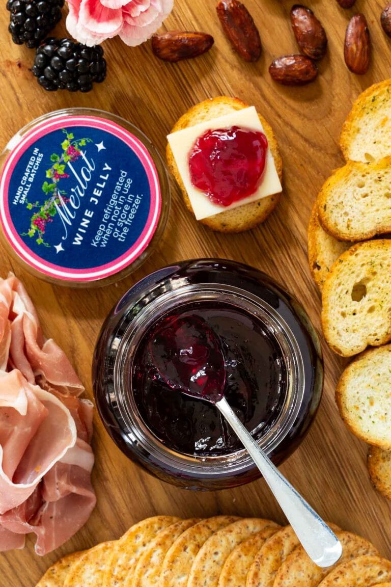 Merlot wine jelly on a wooden board with crackers and nuts