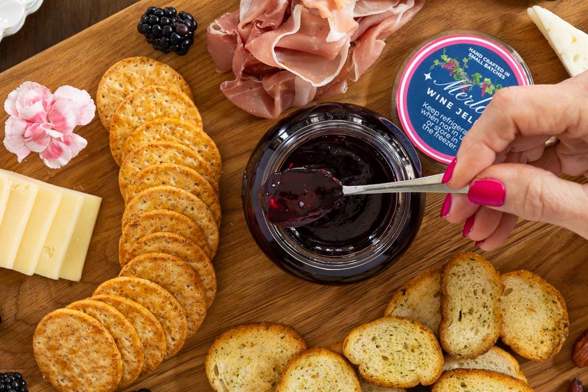 Ridiculously Easy Merlot Wine Jelly - thecafesucrefarine.com Horizontal overhead closeup photo of a charcuterie board featuring Ridiculously Easy Merlot Wine Jelly.