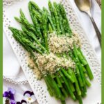 Asparagus on a white platter topped with panko bread crumbs.