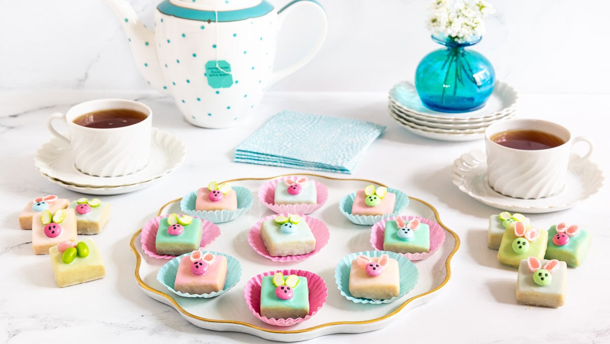 Photo of a plate of Easter Bunny Shortbread Bites surrounded by cups of tea.