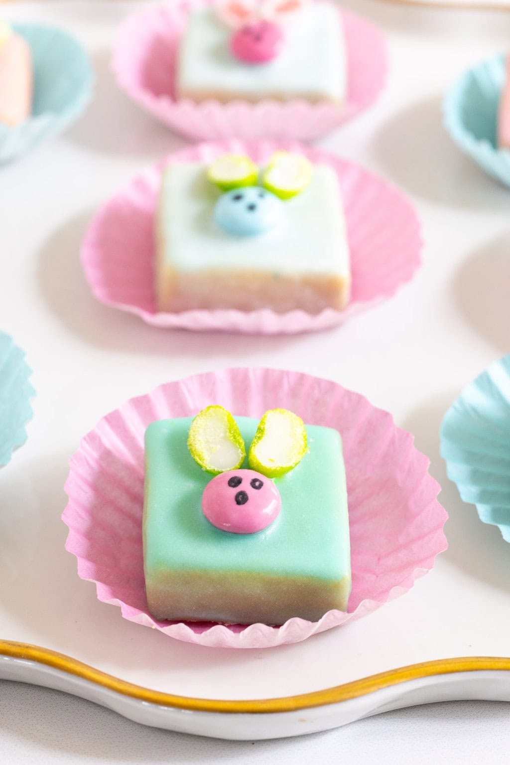 Extreme closeup photo of a plate of Easter Bunny Shortbread Bites with M & M bunnies on the top of each bite.