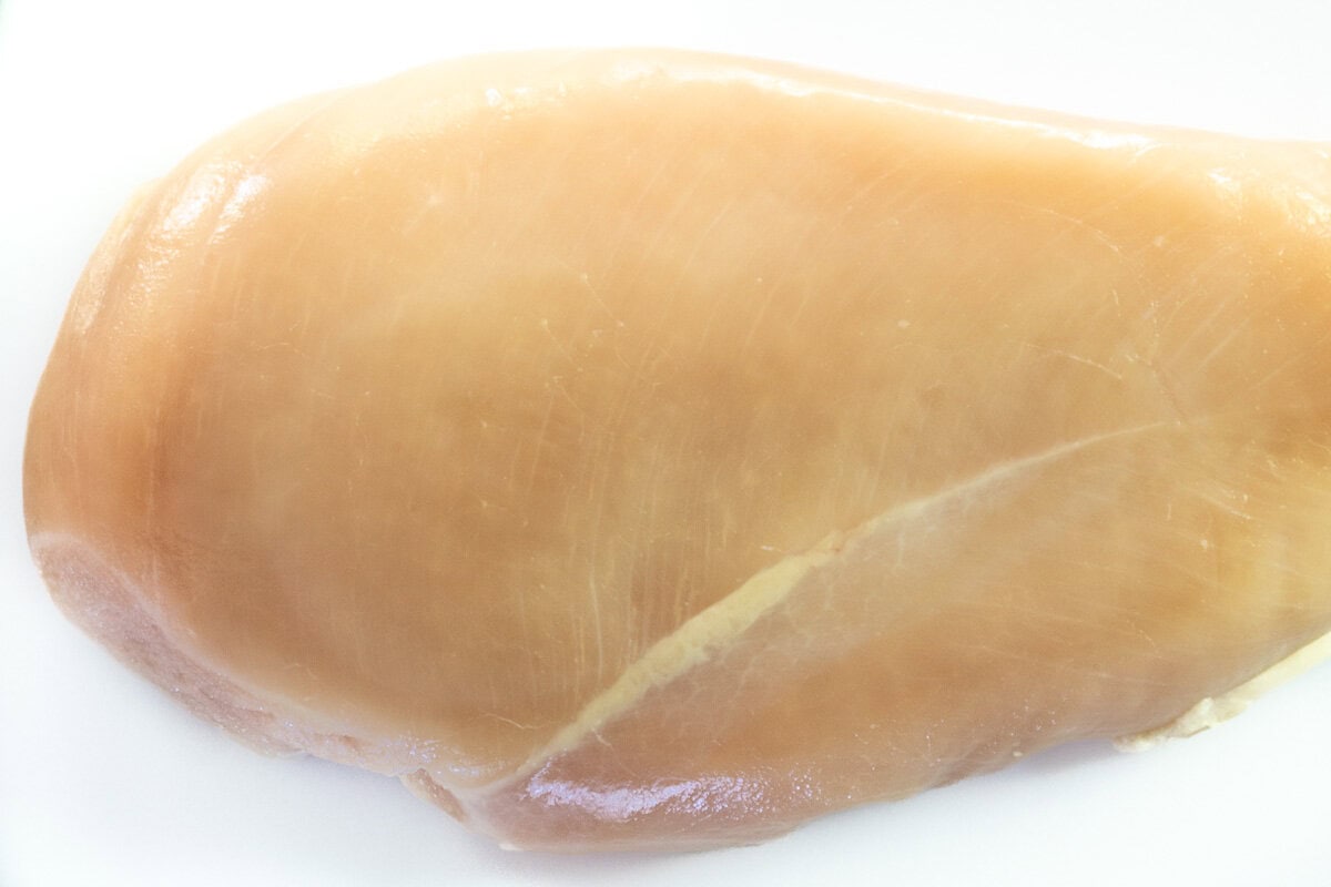 Closeup photo showing the grain lines of an uncooked chicken breast.