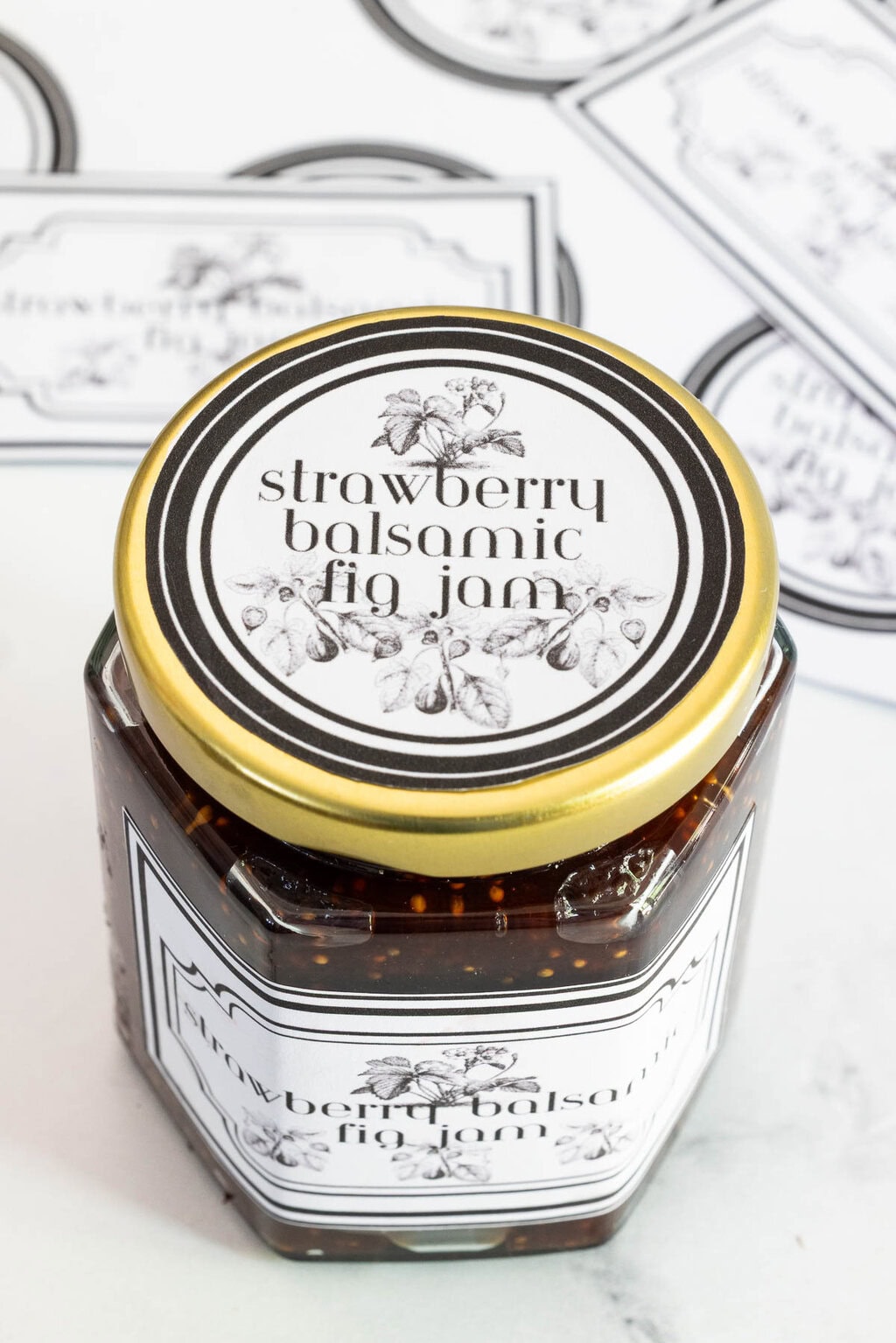 Close-up of of the top of a jar of strawberry balsamic fig jam with a black and white round label.