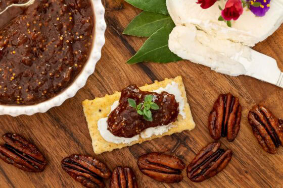Strawberry balsamic jam on a cracker with a smear of goat cheese. Candied pecans as a garnish.