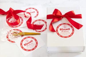 a white box tied up with decorative red ribbon with a custom label for gifting filled with Annie's Biscoff Shortbread Cookies