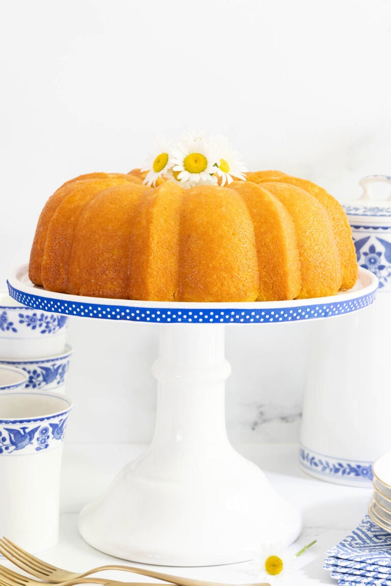 Vanilla Bean bundt cake on a white cake stand with blue and white polka dot ribbon.