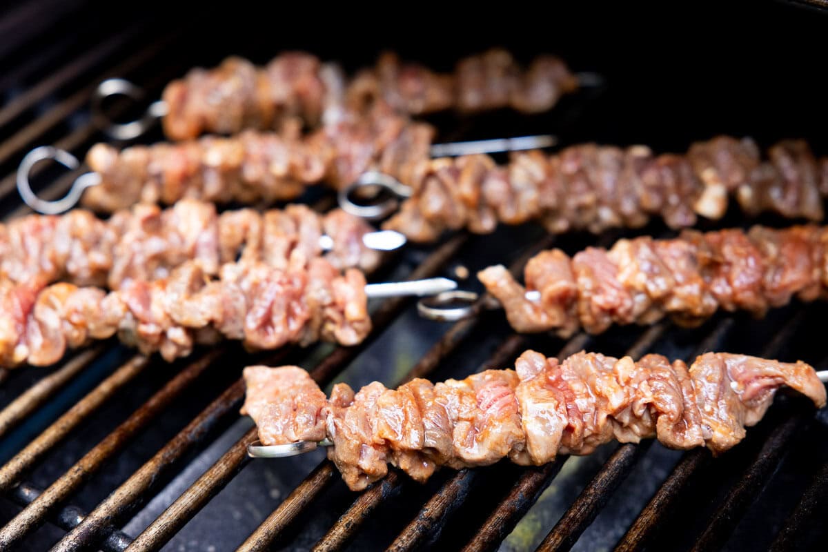 Raw marinated Korean beef skewers placed on a hot grill, ready to cook