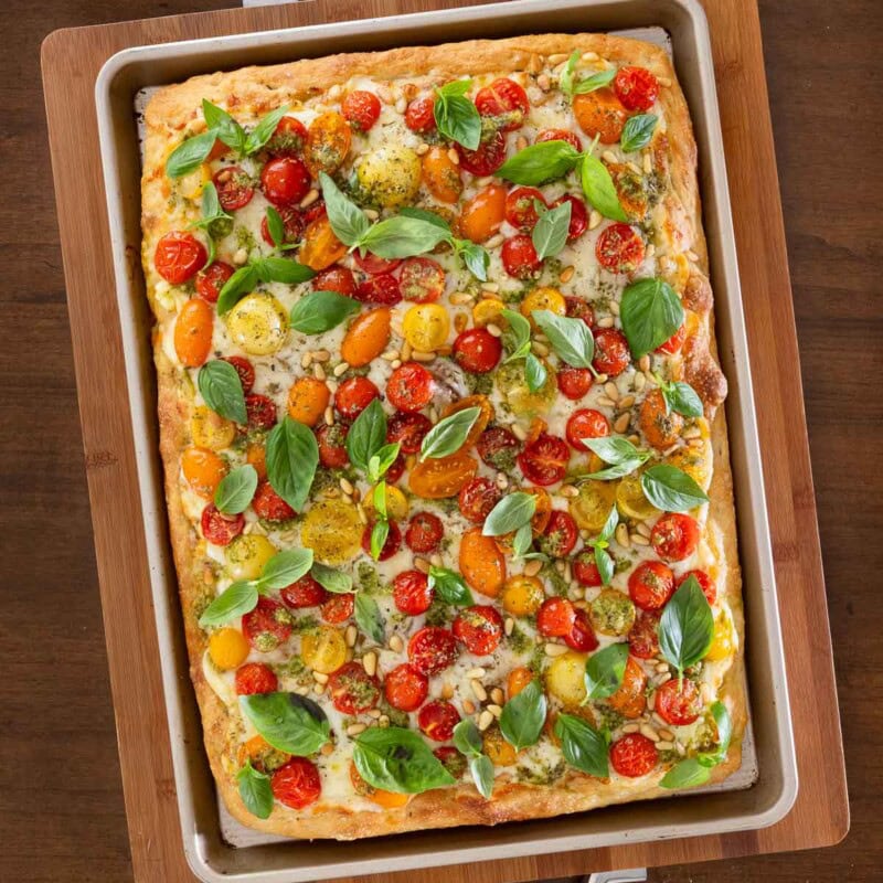 Easy Sheet Pan Pizza Margherita on a focaccia crust with mozzarella, cherry tomatoes, pesto, and fresh basil, styled as a Pinterest pin.