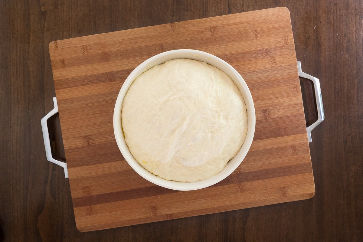 Fully risen focaccia dough in a white bowl, ready to bake into the crust for Easy Sheet Pan Pizza Margherita