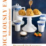 Tall Pinterest pin featuring pumpkin scones drizzled with salted caramel glaze on a white cake stand, styled with blue and white cups, sea salt, and fall flowers.