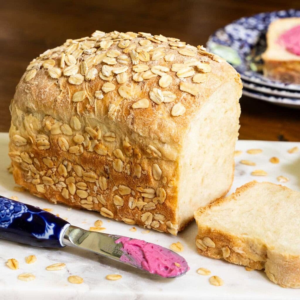 Half a loaf of homemade bread sitting on a counter next to a butter knife.