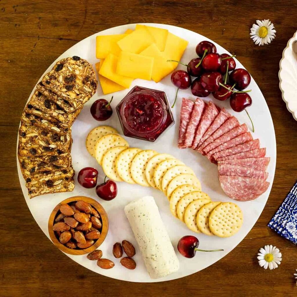 Charcuterie board arranged with several varieties of crackers, cheeses, and Italian meats.