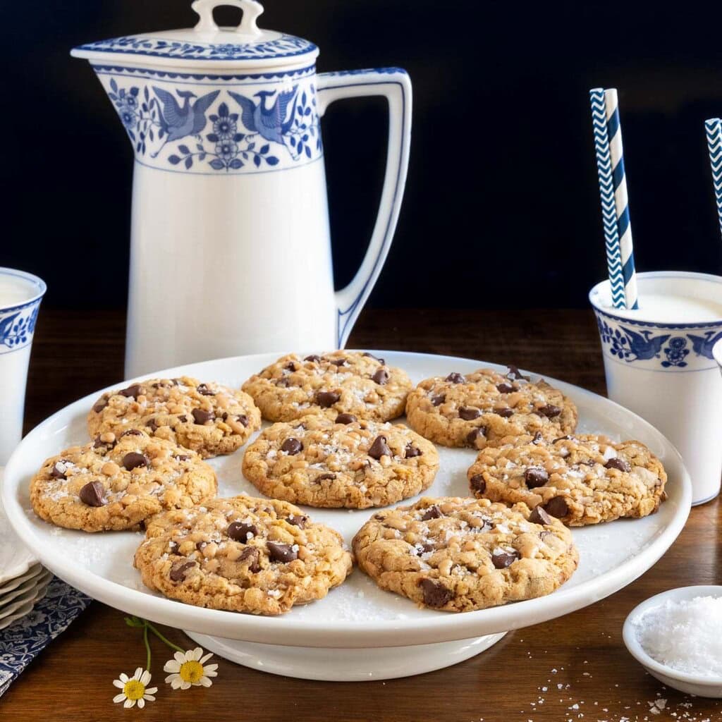 White platter full of homemade cookies next to a large pitcher of milk.