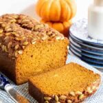 Pumpkin bread sliced on a blue and white kitchen towel.