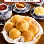 Potato rolls in a bread basked with small bowls of jam, honey and butter