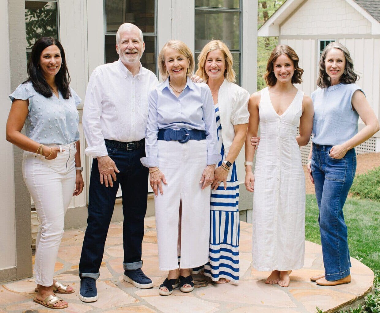A group of six people wearing blue and white, standing on an outdoor stone patio