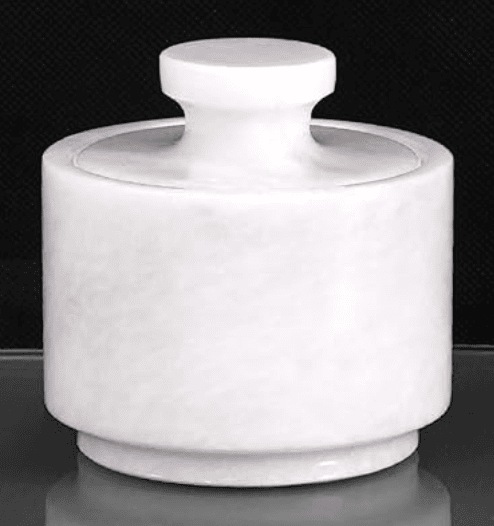 a white marble salt cellar with lid set against a black background