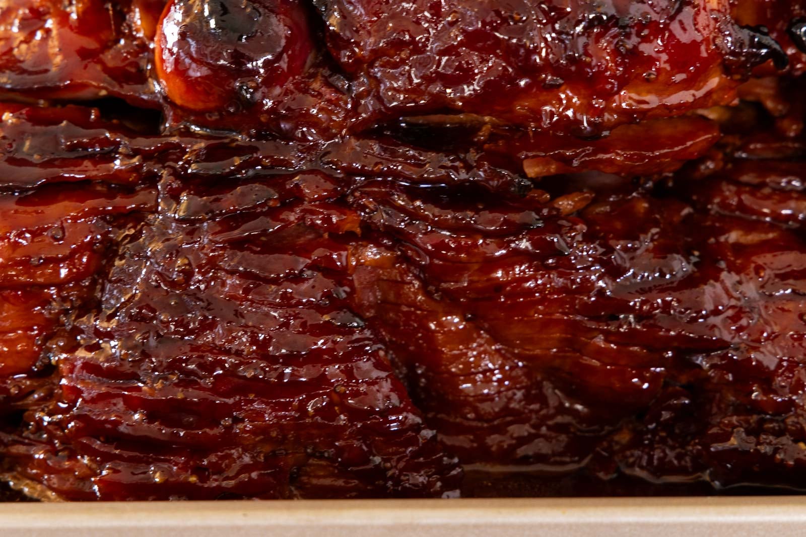 Close-up of pepper jelly glazed spiral ham showing a glossy, caramelized sweet-savory glaze.