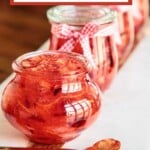 Glass jars filled with homemade red jam arranged on a marble board with a spoon, styled for holiday gifting with free printable labels
