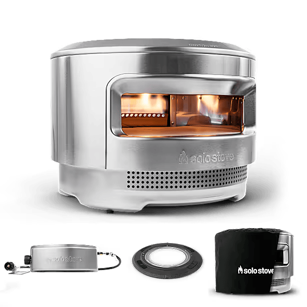 Solo Stove Pi outdoor pizza oven with a fire burning inside and accessories beside