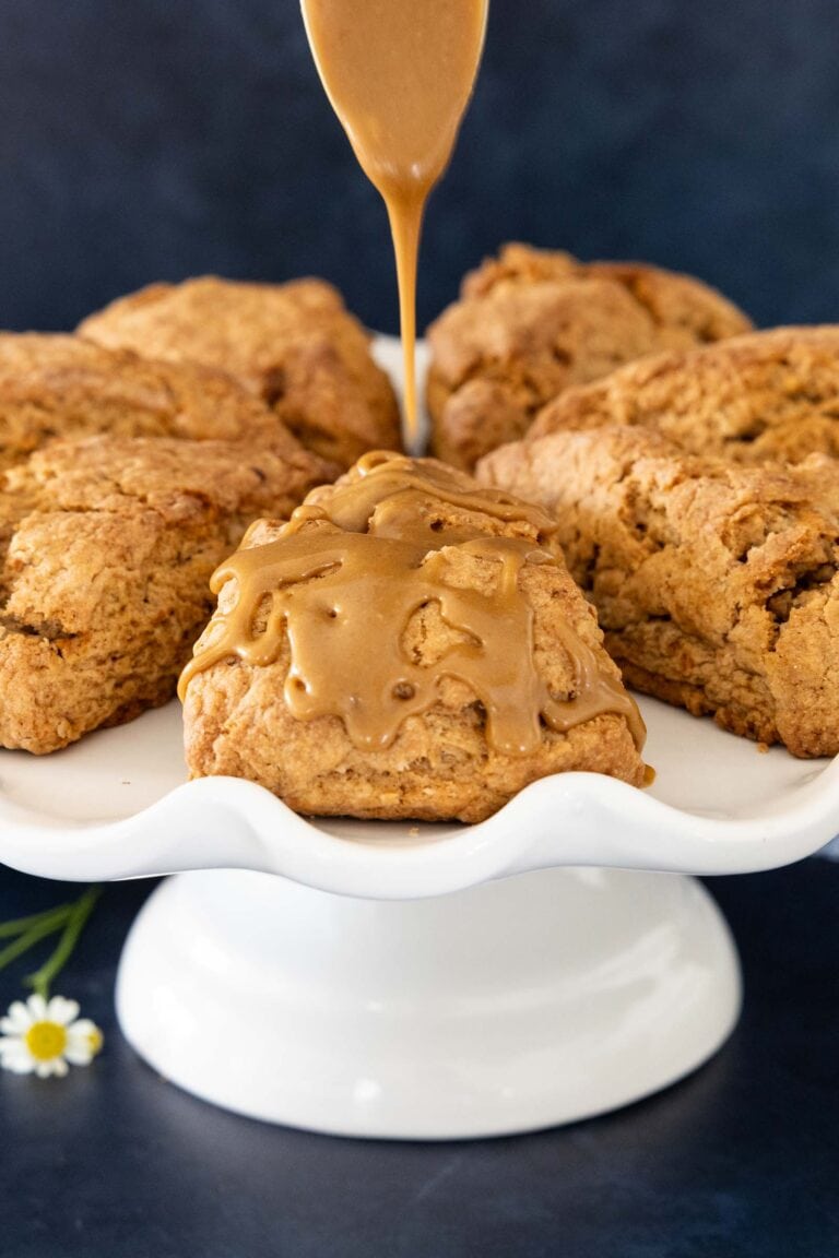 Carrot Cake Scones on a white cake stand with caramel icing drizzled on top.