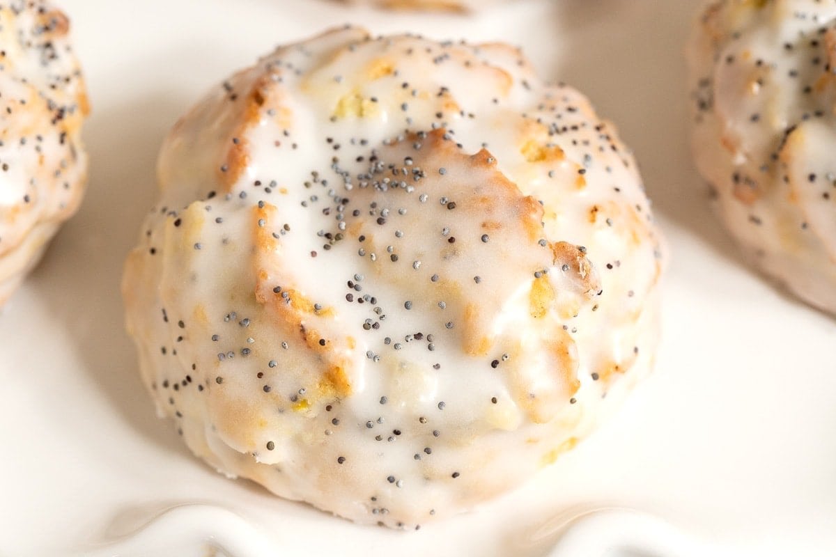 Close-up of a glazed lemon poppy seed scone showing tender crumb and lemon zest beneath the sweet icing.