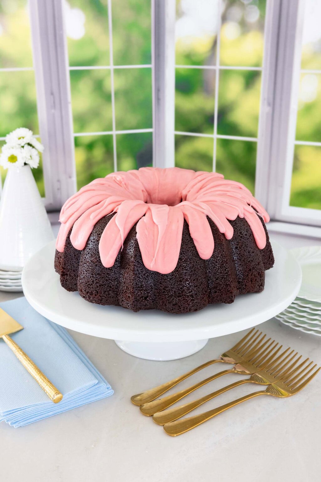 Chocolate pound cake with strawberry icing that is too thick sitting on top of the cake.
