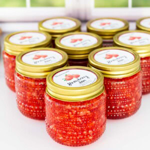 Jars of Strawberry Freezer Jam lined up on a counter.with labels on top of each jar.