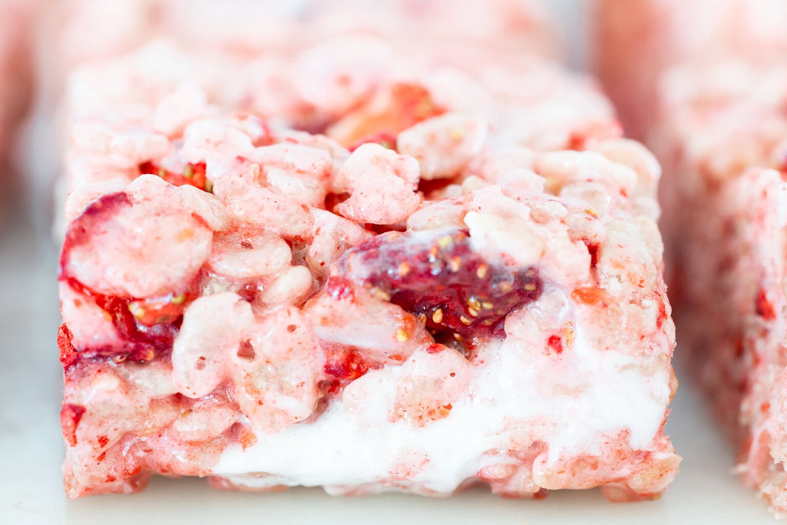 Close-up of strawberry rice krispie treat showing gooey marshmallow layer and pieces of freeze-dried strawberries