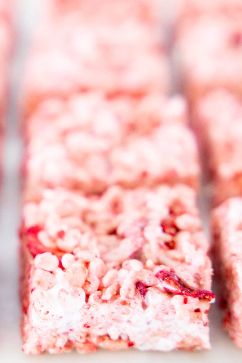 Soft-focus close-up of strawberry Rice Krispie treats showing marshmallow texture and pieces of freeze-dried strawberries.