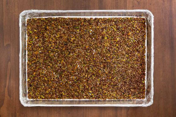 Overhead view of baked Maple Pistachio Brittle spread across a foil-lined baking sheet after baking until golden brown and caramelized.