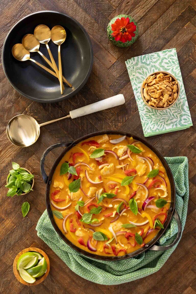 Lemongrass Coconut Chicken Curry in a cast iron skillet with bowls, spoons and napkins