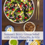 Pinterest pin for Summer Berry Green Salad with Maple Pistachio Brittle featuring fresh berries, greens, pickled red onions, Honey Lemon Mint Dressing and crunchy brittle on a wooden table.
